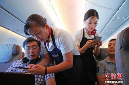 資料圖：乘務(wù)員們?cè)诳团搩?nèi)為旅客調(diào)試機(jī)上上網(wǎng)功能。<a target='_blank' ><p  align=