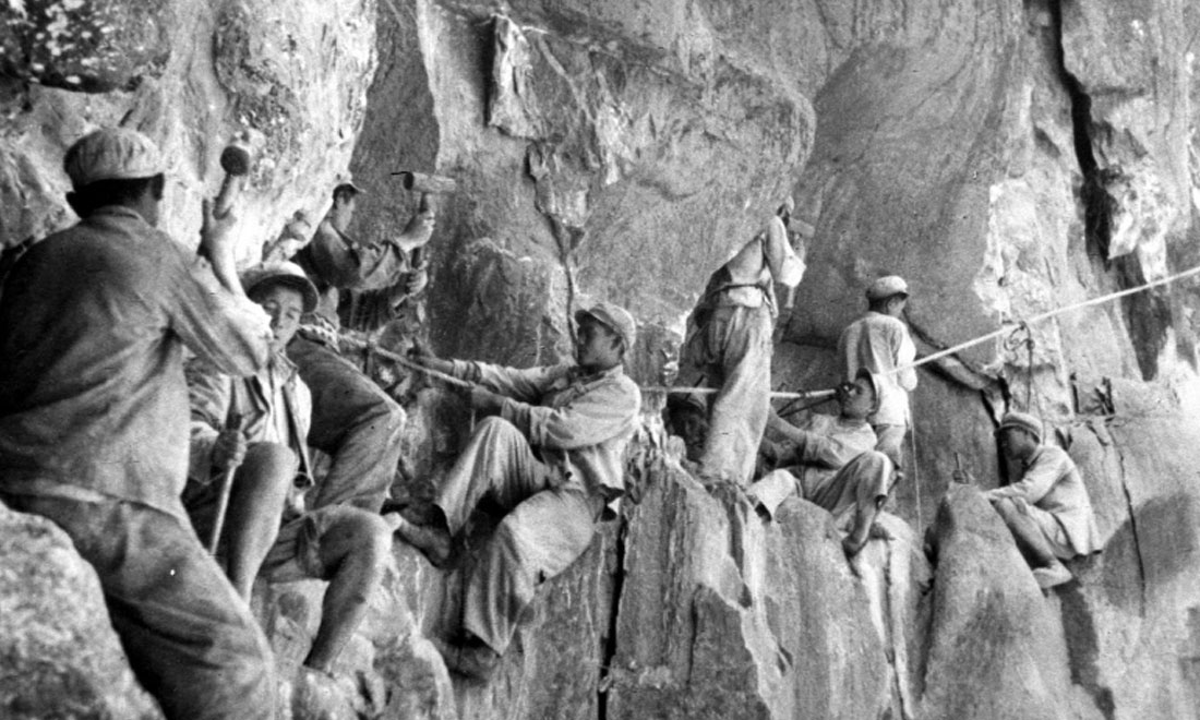 1954年，修筑康藏公路的解放軍戰(zhàn)士們?cè)谂瓋砂兜膽已露副谏媳偕街?。新華社稿 李萬(wàn)春、張加里攝